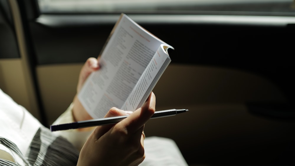 Efficient Reading: Person in Gray and Black Long Sleeve Shirt Engrossed in Book