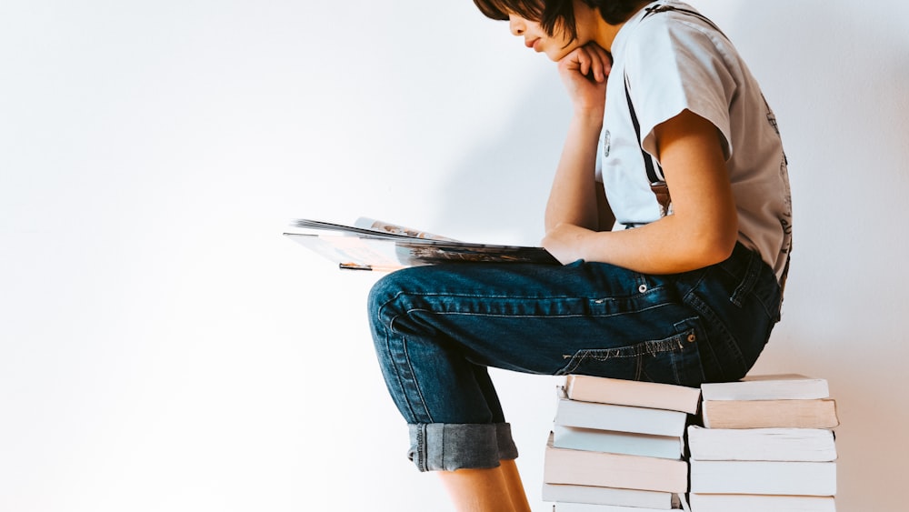 Reading Woman in Gray T-shirt and Blue Denim Jeans