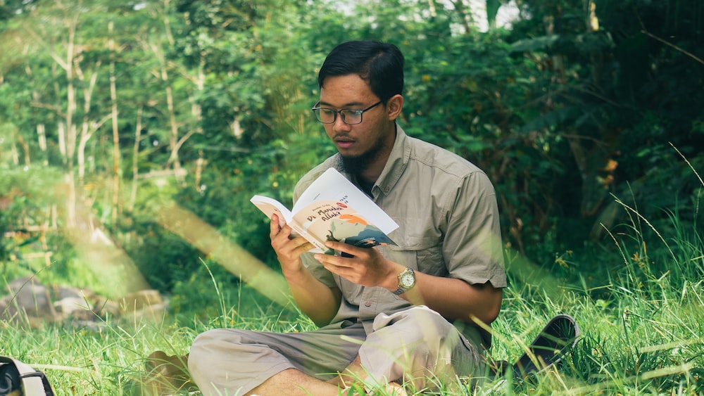 Reading by the River: Young Man Engrossed in a Book